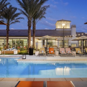 Resort-style swimming pool swimming pool with lounge chairs and a building in the background