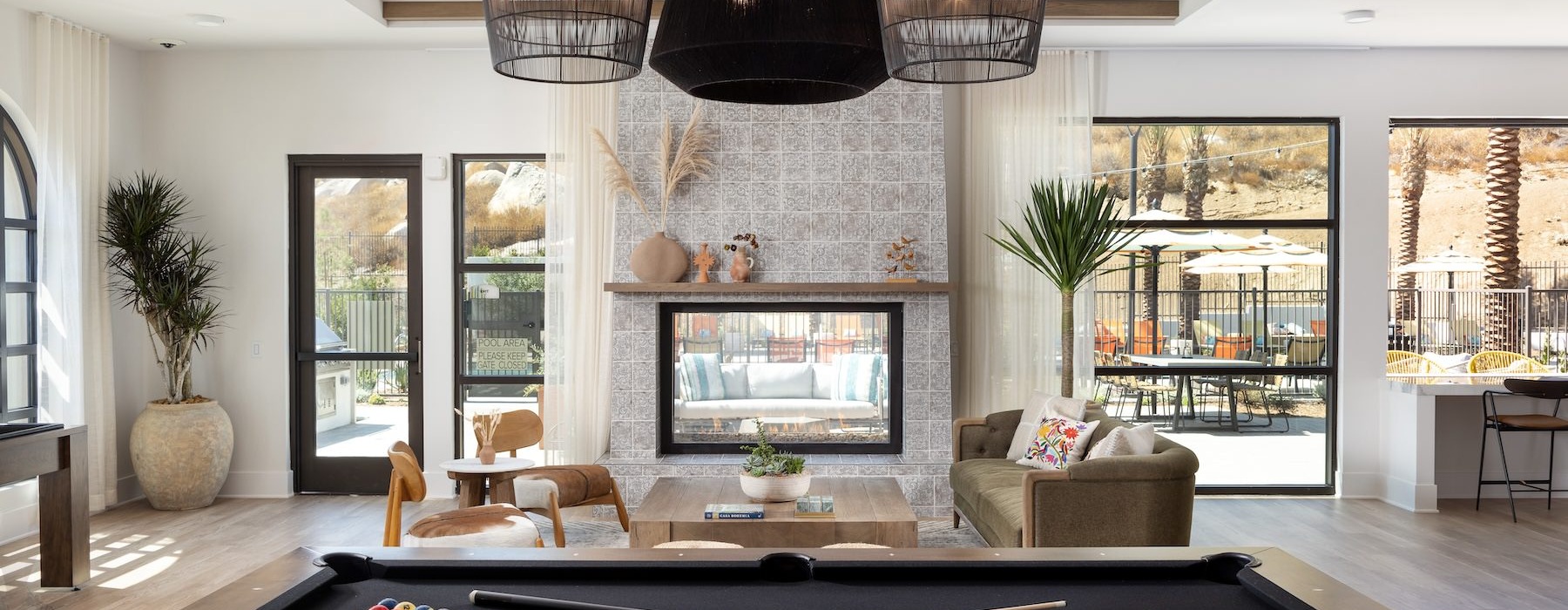 pool table in social room with a fireplace and large windows